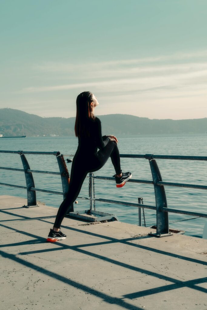 woman stretching on a pier overlooking the water