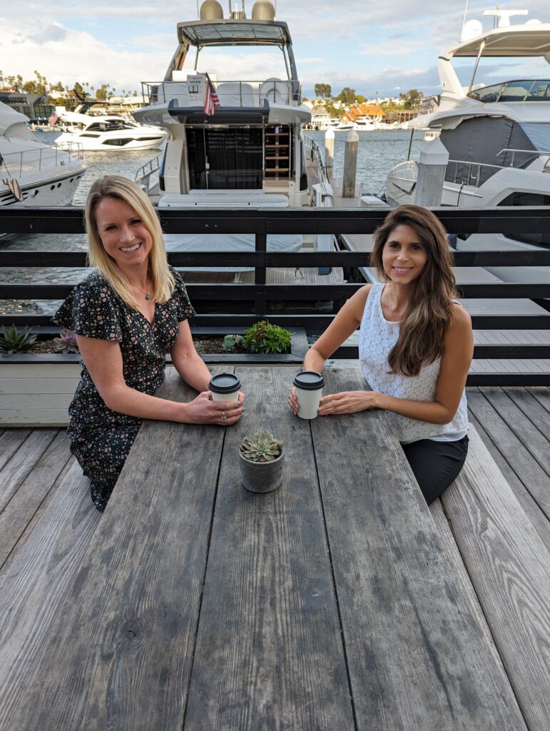 two women sitting at a table in front of a boat in Orange County, CA